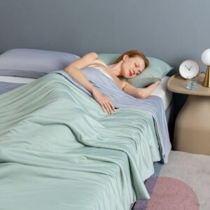 Light green cooling blanket draped across a bed